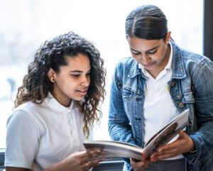 Two students are looking at a book together.