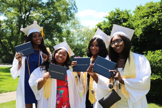 Happy graduates hold up their diplomas.