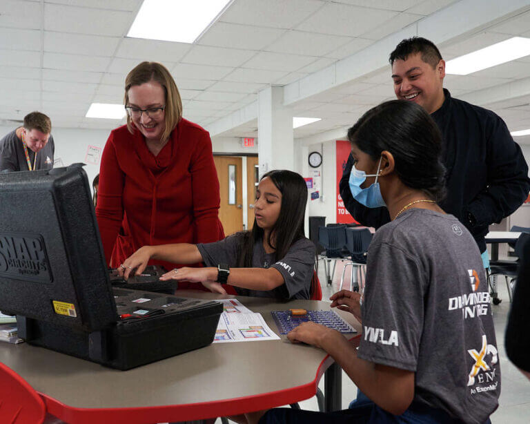 YWLA students and staff unpack new STEM equipment in a classroom.