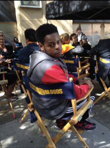 Eric Arriola sitting in an actor's chair on the set of Blue Bloods.