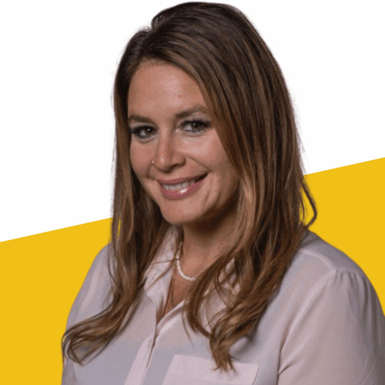 Woman with long brown hair wearing a light pink blouse and a pearl necklace, smiling in front of a white and yellow background.