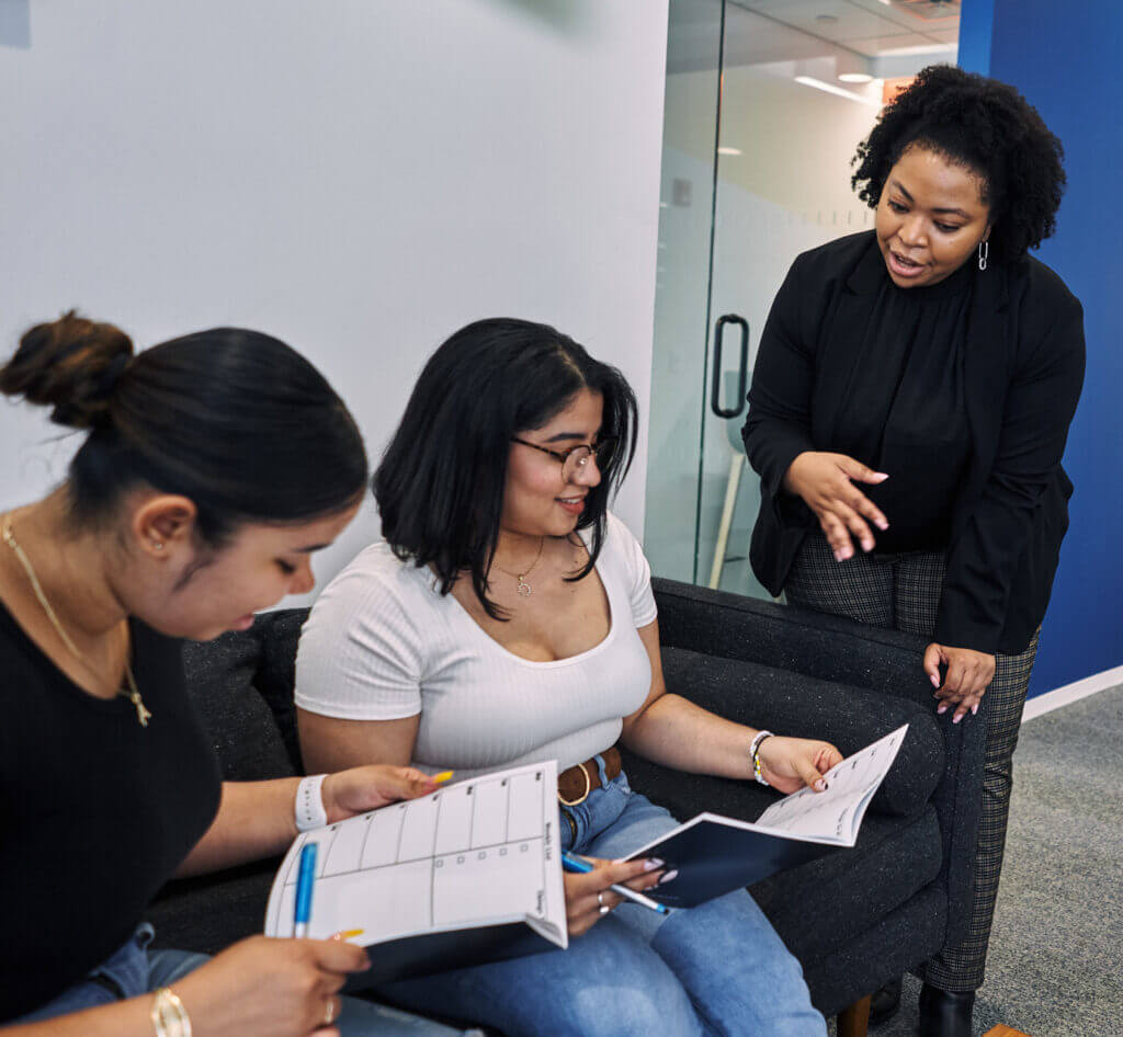 Gabrielle Lloyd is talking to two college students. They are looking at agenda planners. 