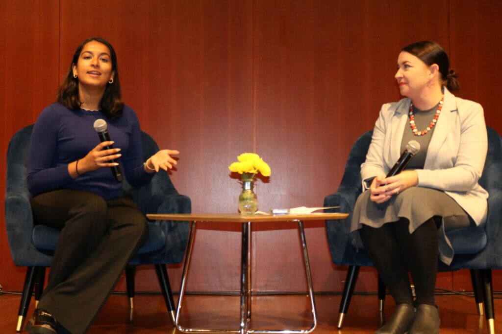 Melissa Kilby and Riya Goel sit on chairs in conversation