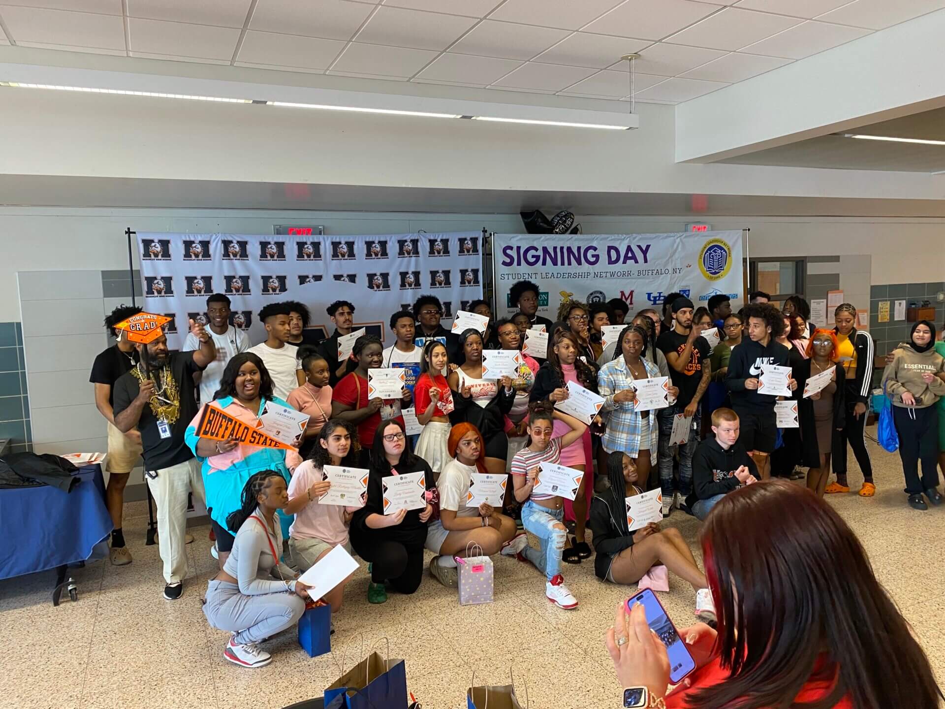 McKinley High School students hold up college pennants and acceptance letters on College Signing Day