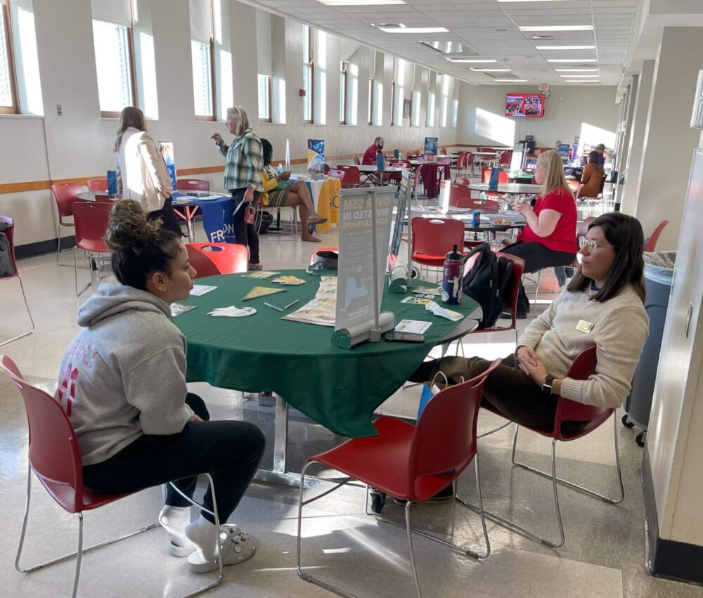 A student and an admissions representative sit down to talk together during a college fair
