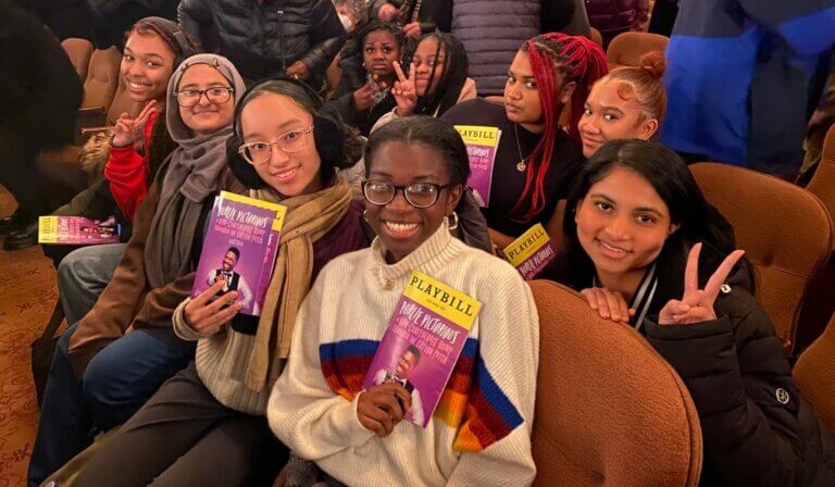 Students hold up Broadway play booklet for Purlie Victorious in their theater seats