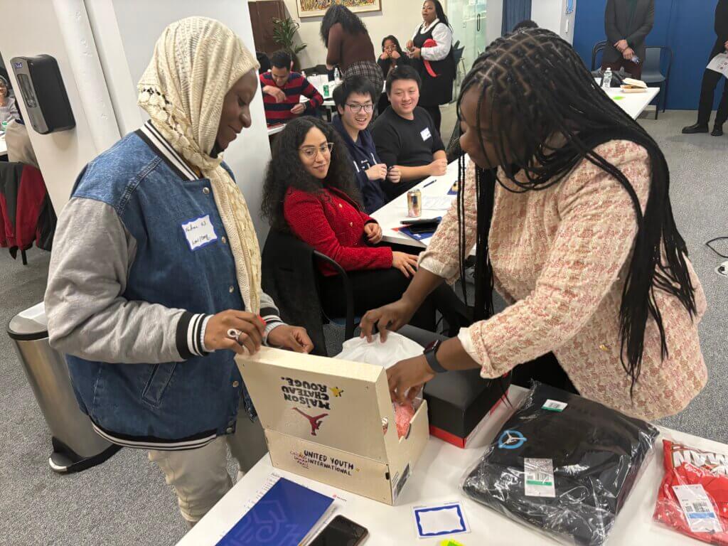 Alumni in headscarf and denim jacket picks a raffle prize from the table