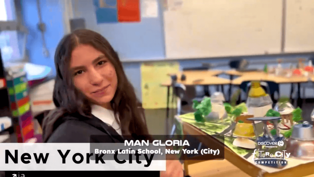 Student in science classroom, with a model of a green city on the table