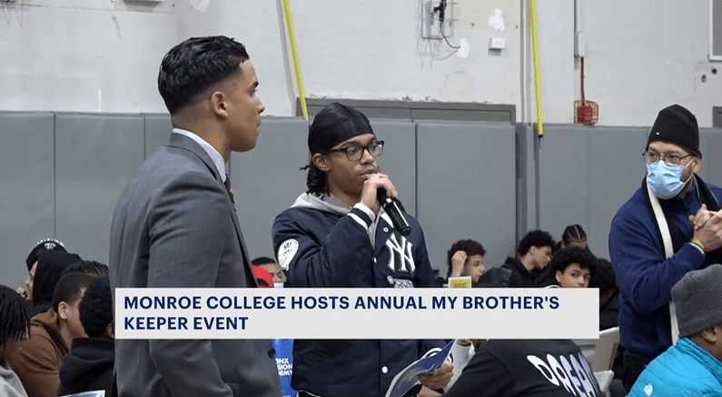 Student talks into microphone in college gymnasium with other young Black male students