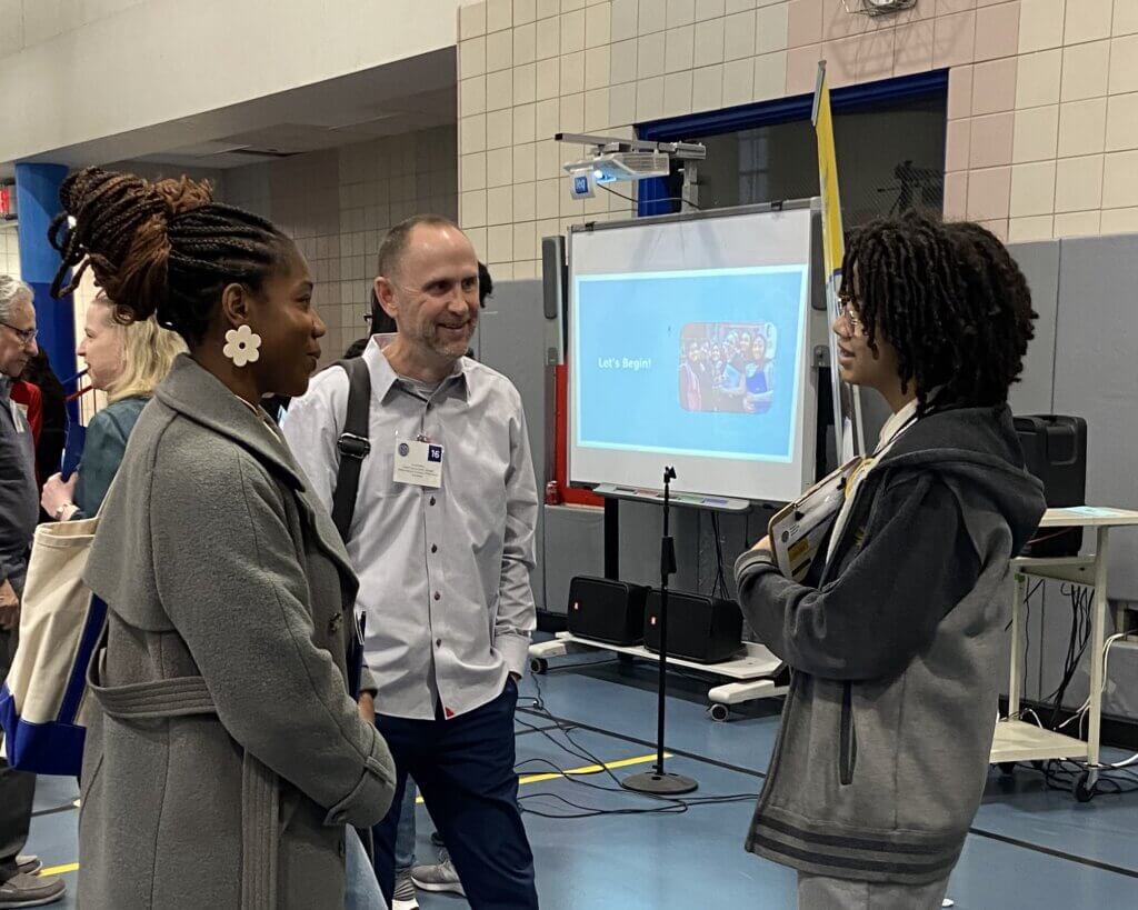 Two adults and a student practice talking about career paths in the gymnasium
