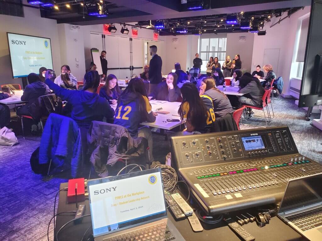 Students are seated in small groups, with a lighting system in foreground, for event about careers in music