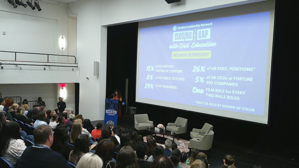 Auditorium setting, with statistics of the gender gap on screen