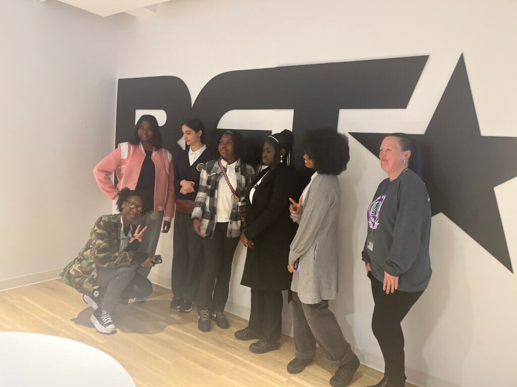 Students strike a pose in front of a wall with a large BET sign (Black Entertainment Television)