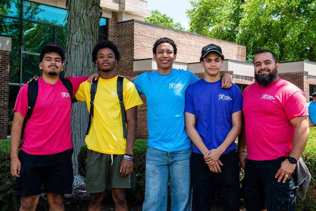 A counselor and four of his students pose for a photo outdoors