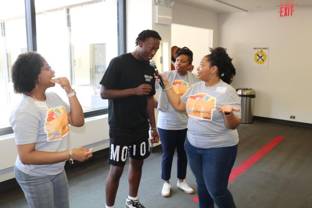 Male student speaks into microphone held by a staff member