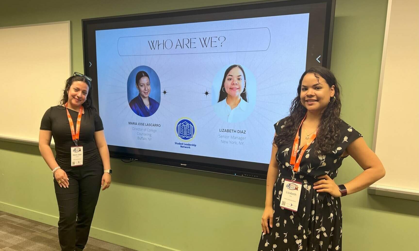 Two adults stand in front of a presentation screen at a conference