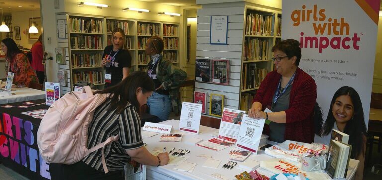 Young woman signs up for information at a girls' education program table