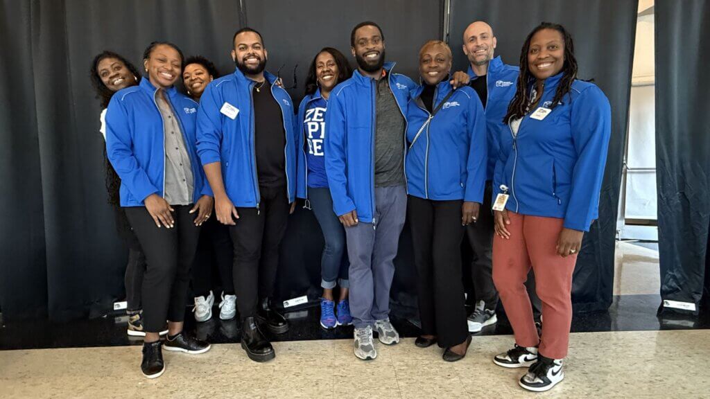 College access staff with matching blue jackets pose for photo at a college fair