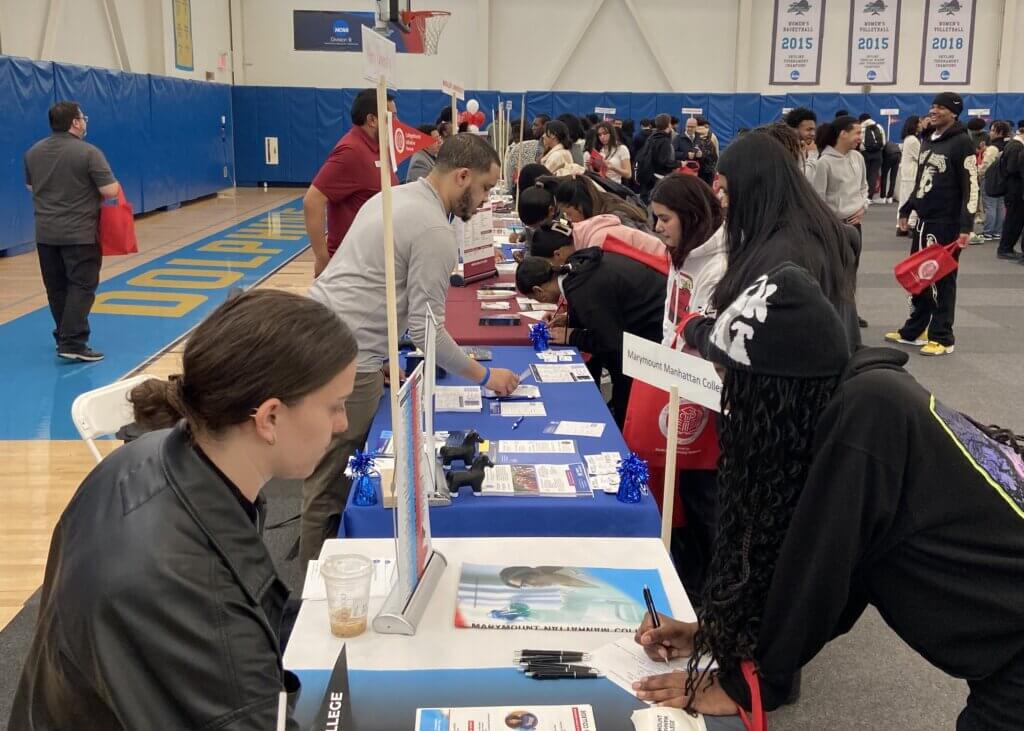 Students fill out college inquiry cards at various booths in a college fair
