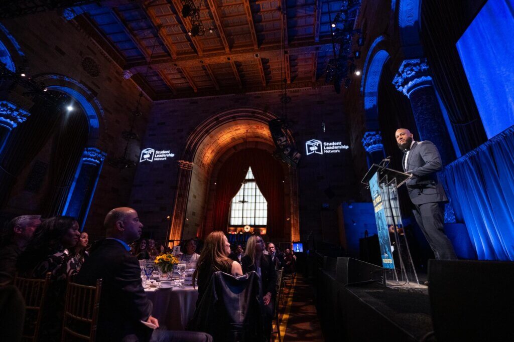 Event presenter Jon Roure speaks from the podium