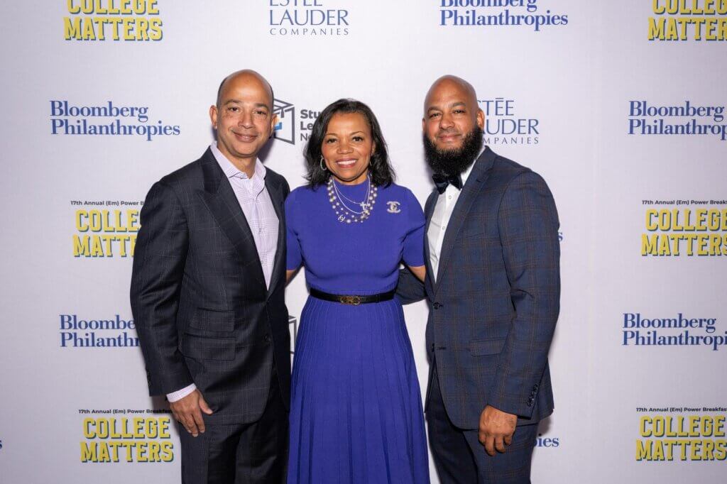 Event presenters pose for photo in front of event backdrop