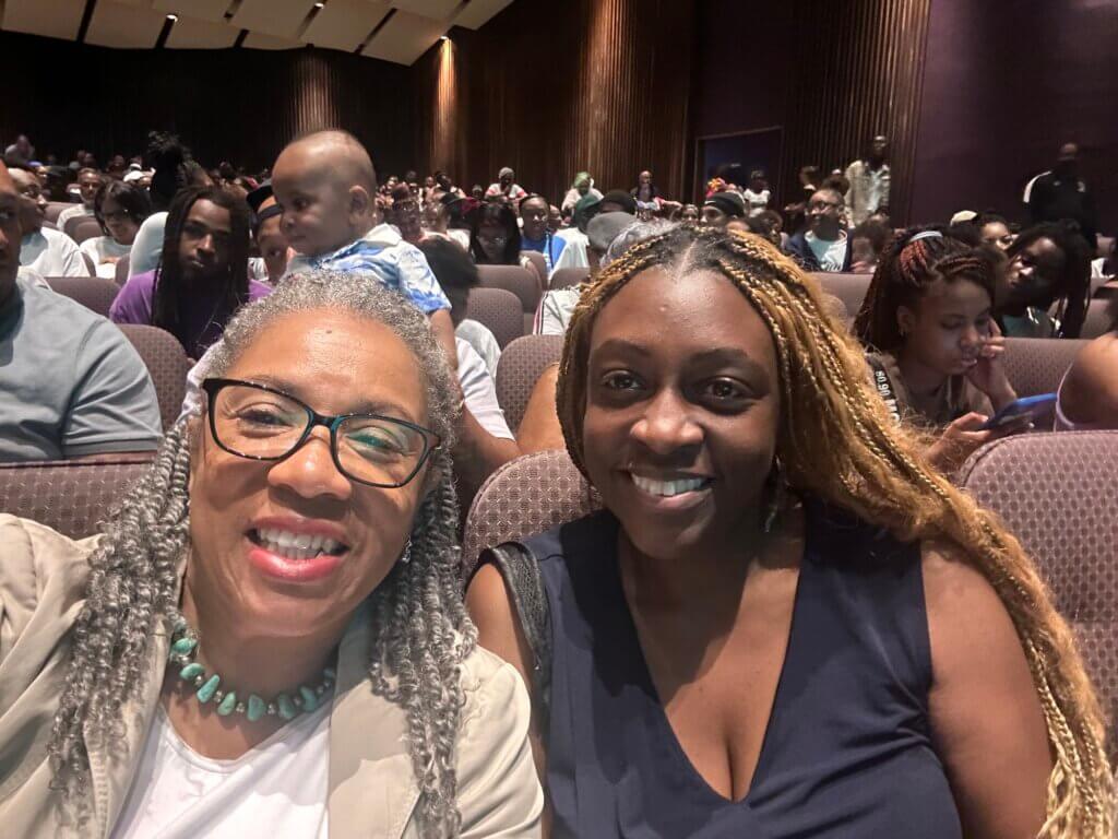 Two staff members in audience during girls' school graduation