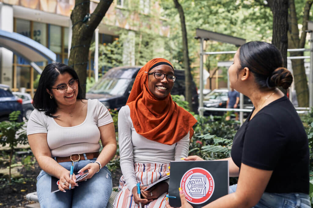 Three young women in a peer mentorship program called CollegeJourney converse on a college campus