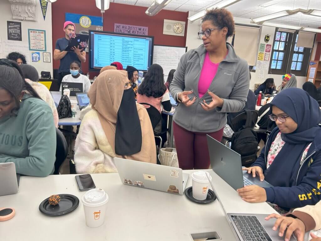 Staff member talks with students working in a classroom