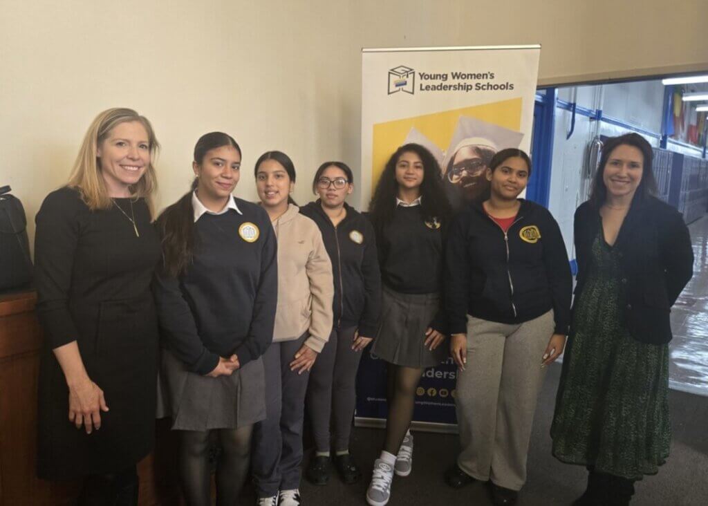 Group of students and volunteers pose for photo in a school hallway