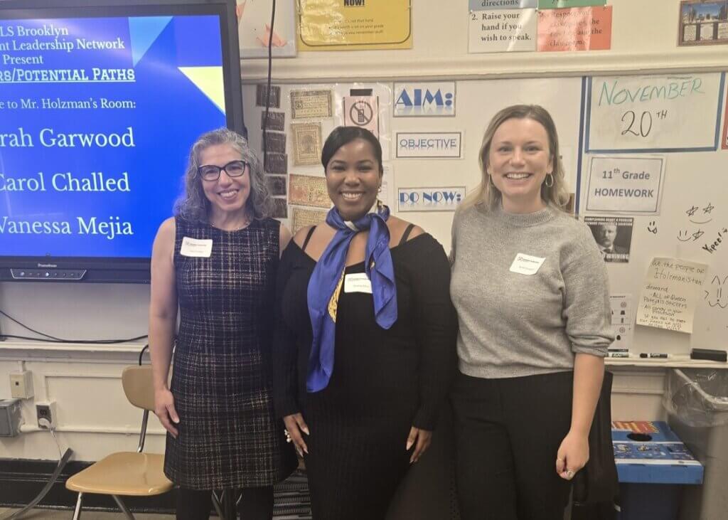 Three female volunteers present at front of classroom