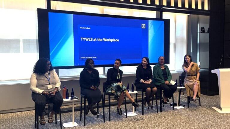 Panel discussion with adults seated in a row in front of the room