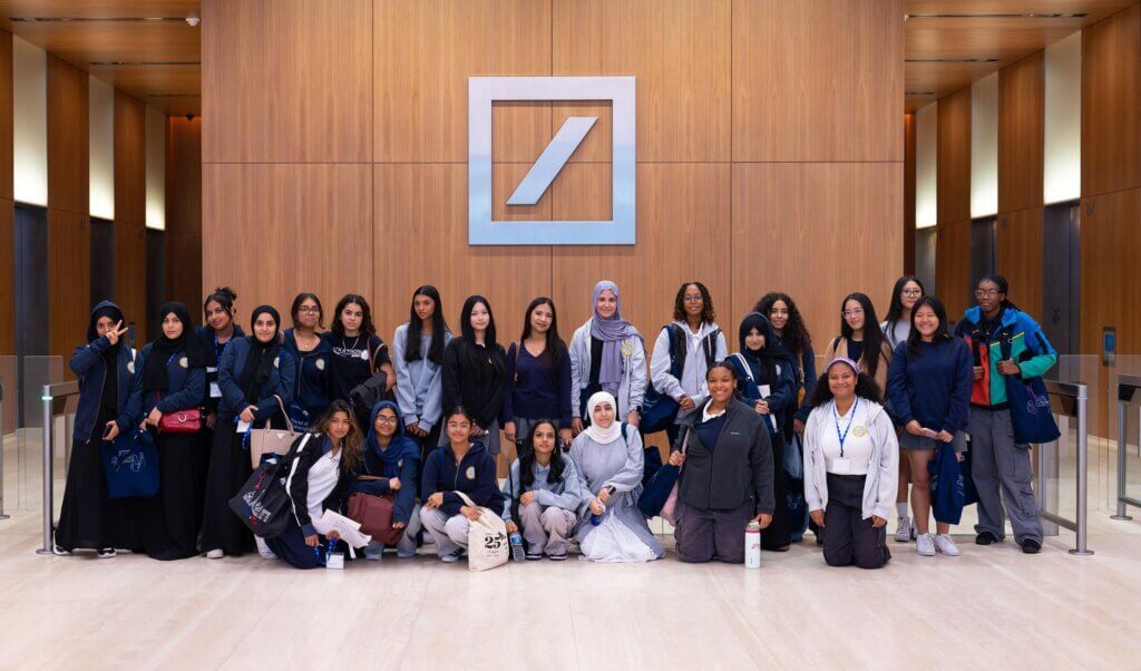 Students gather in front of Deutsche Bank logo in lobby for a photo