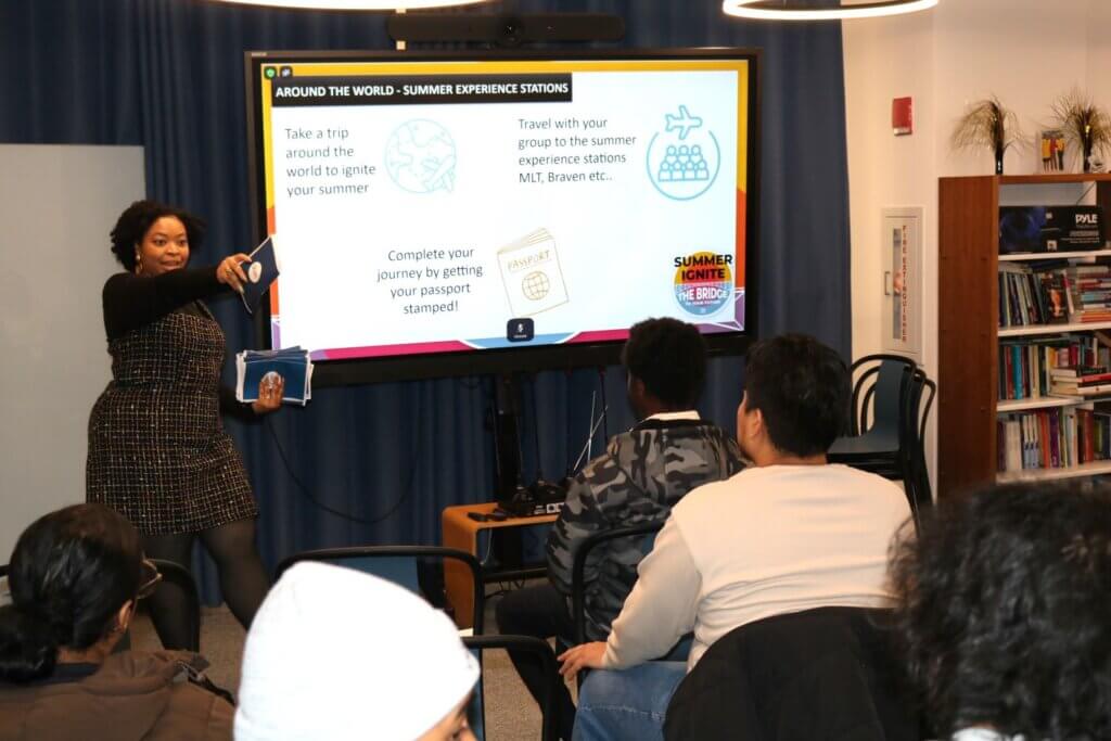 Staff member holds up activity brochures at front of room