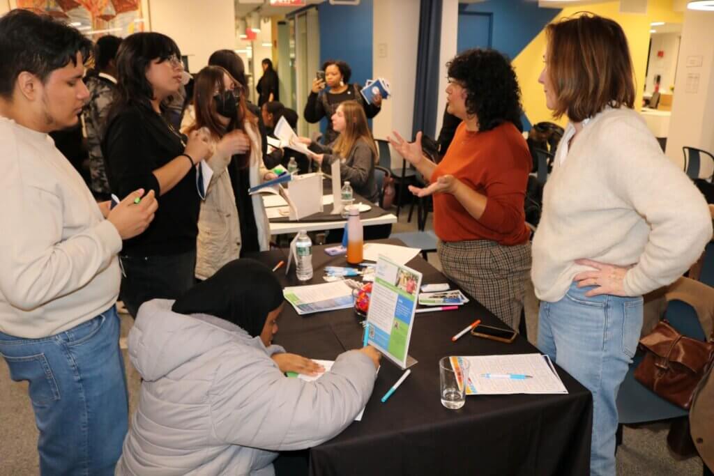 Student signs up on sheet of paper at a program partner table
