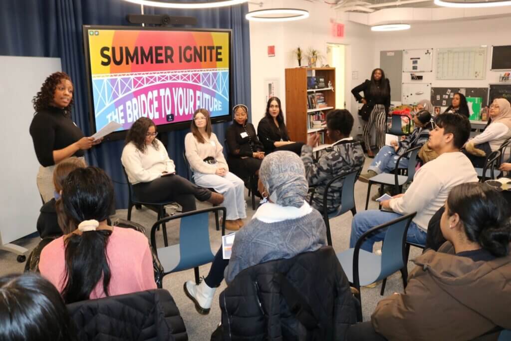 Alumni panelists are seated in front of room with students in semi-circle around them