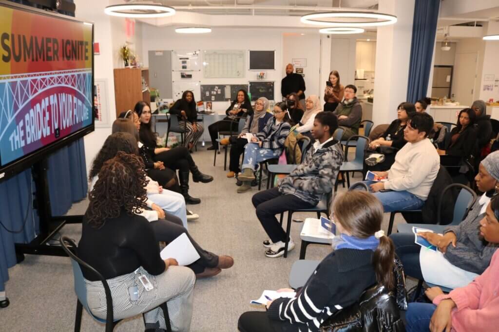 Alumni panelists are seated to the left while students are seated in semi-circles to the right
