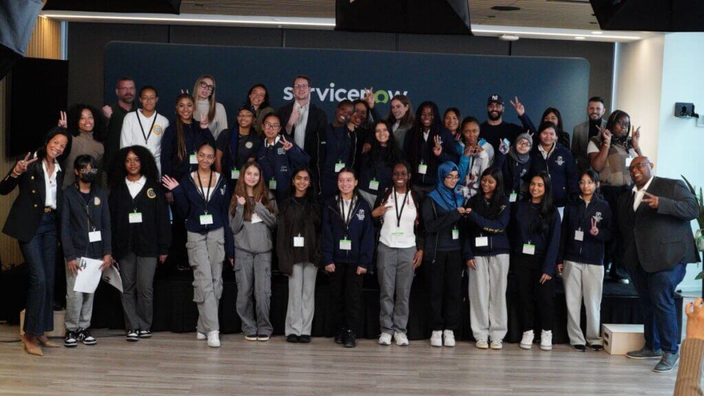 Group of about 35 students and adult volunteers pose for a photo, some are holding up peace signs with their hands or waving