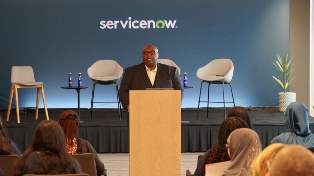 Rob Robinson stands at podium in front of room, addressing the students seated in the audience