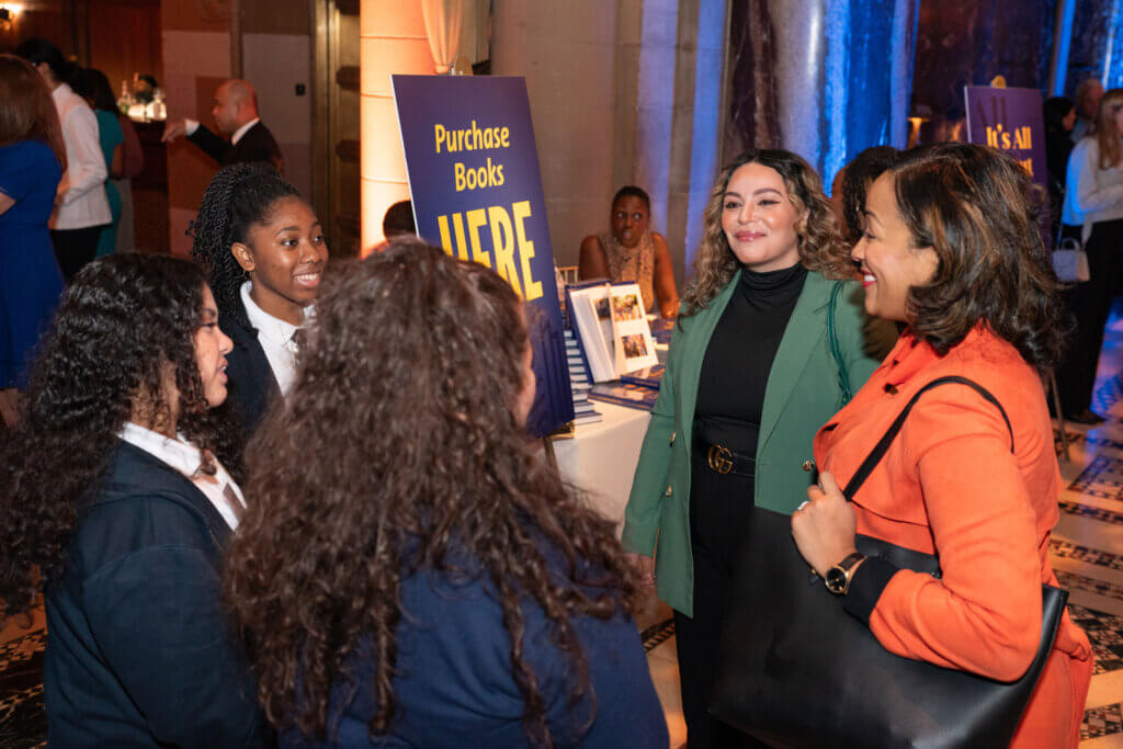 a group of three students speaks to two smiling adults