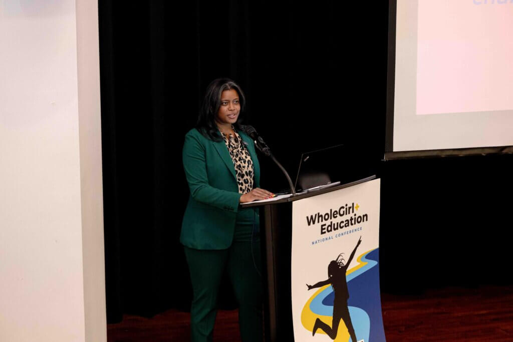 Laura Moore speaks on a podium on stage