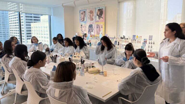 students in lab coats and gloves mix ingredients for customized lip glosses