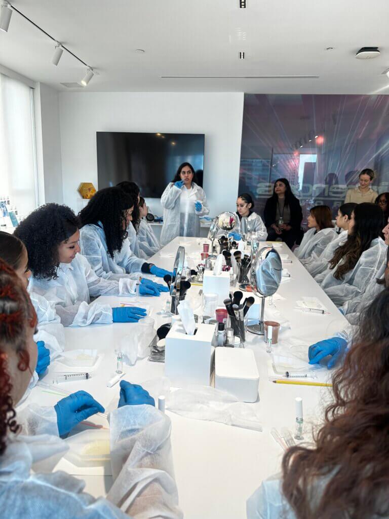 Students wear lab coats and gloves in a lab setting