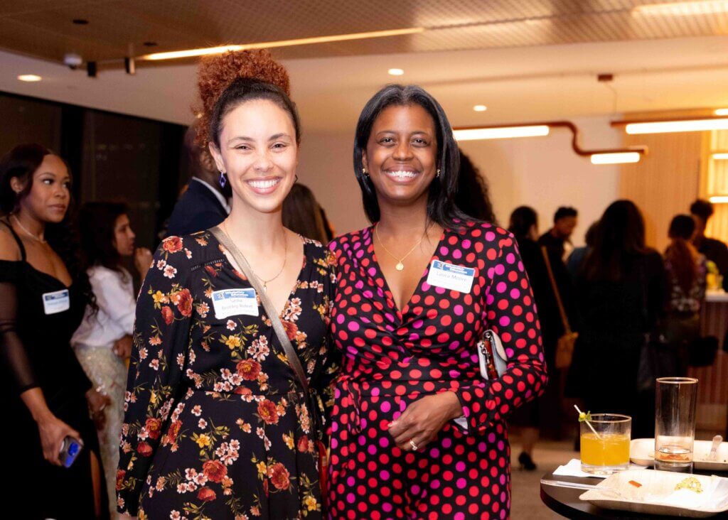 Two women smile confidently to camera