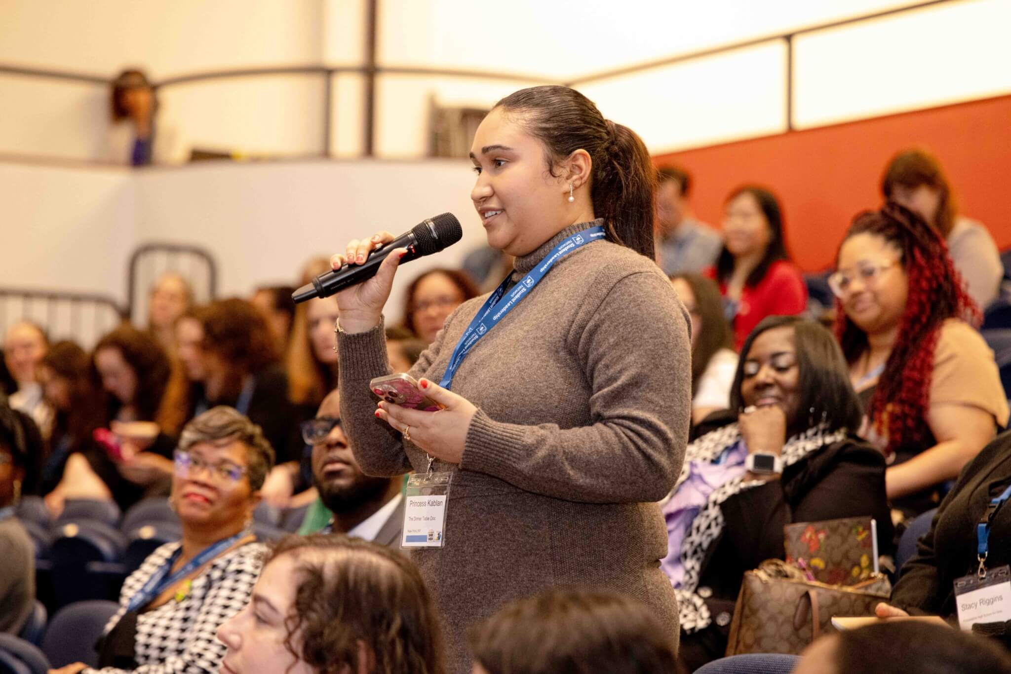 women stands up in audience with microphone