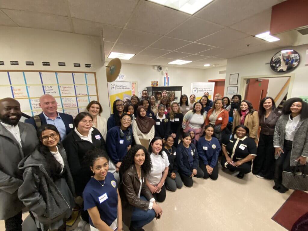 group photo of adult volunteers and students in hallway of a school