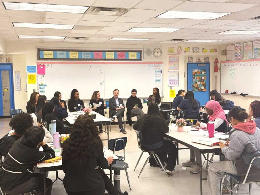 panel of adult volunteers at front of classroom while students are seated at their desks
