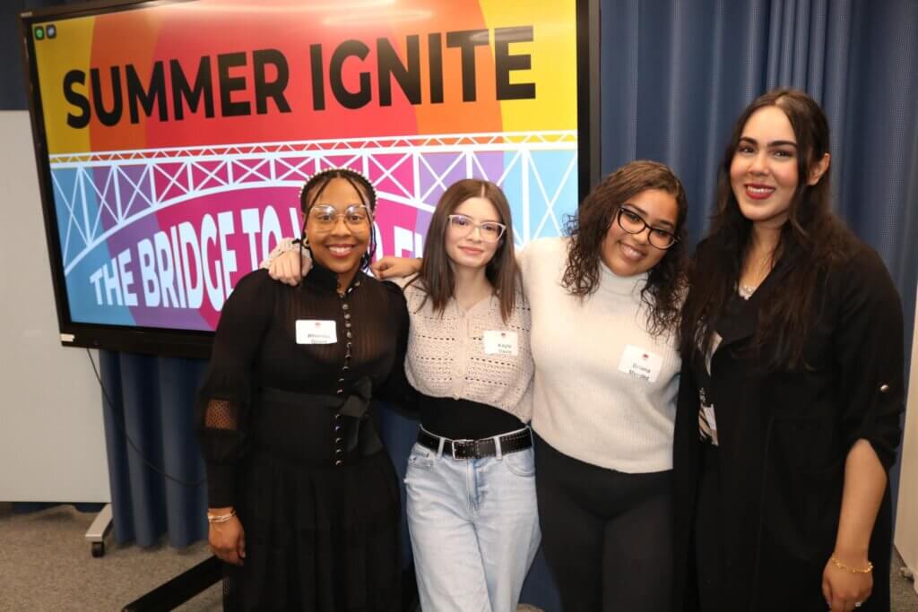 Four young women pose in front of a screen after sharing career advice with students