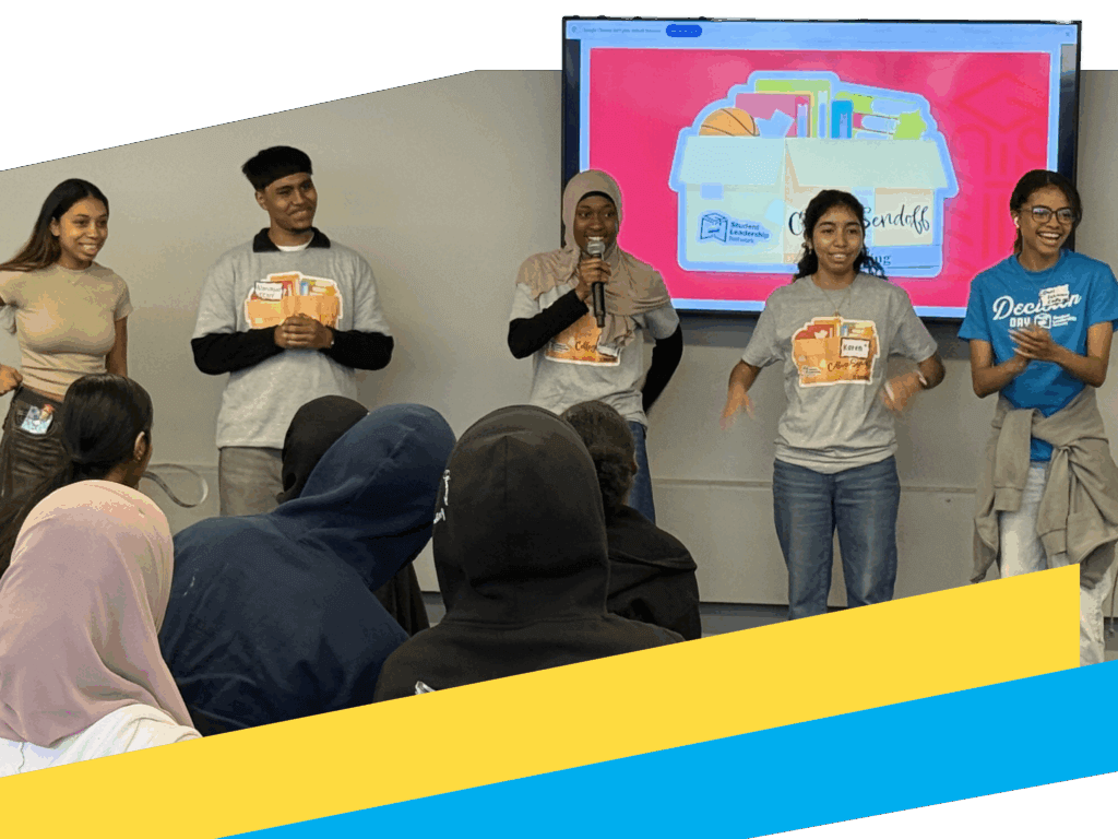 Five College Transition Coaches stand in front of a classroom, presenting near a screen displaying colorful folders and documents.