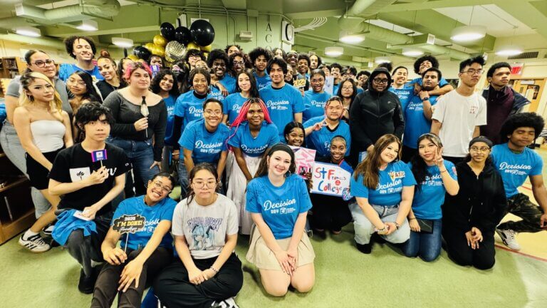 A large group of students, showcasing student leadership, pose together indoors, many wearing matching blue Decision Day 2023 shirts; some hold signs and balloons are visible in the background.