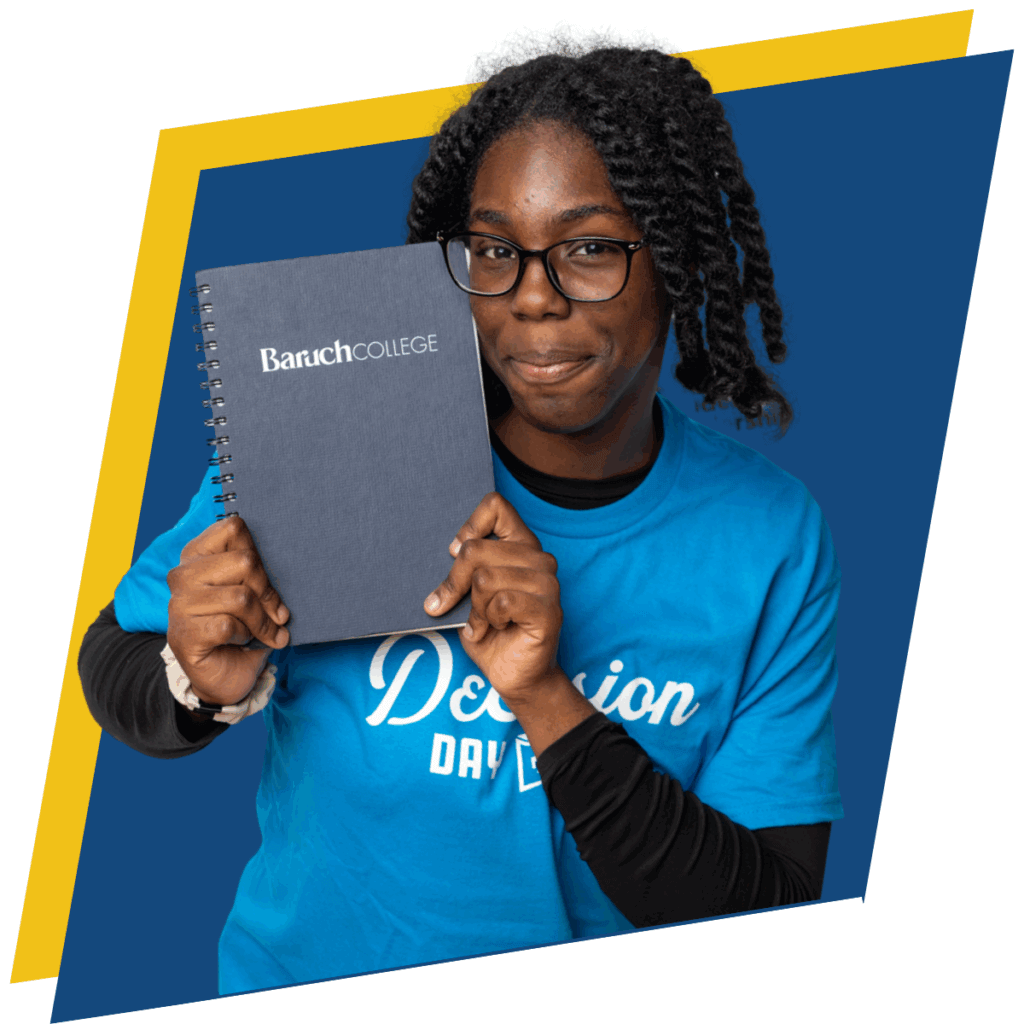 Smiling female student with braided hair and wearing glasses, is holding up up a notebook that says Baruch College on the cover